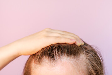 Girl touching her hair close-up on light pink background, hair loss concept.