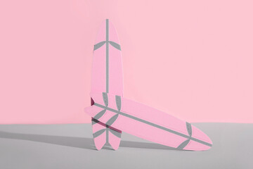 Mini surfboards on grey table against pink background