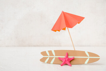 Mini surfboard with umbrella and starfish on light background