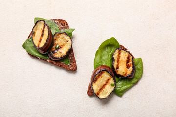 Toasts with delicious grilled eggplants on light background, top view