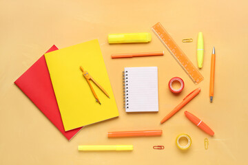 Notebooks with different school stationery on orange background