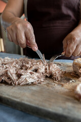 An adult Hispanic woman is chopping beef on a kitchen table
