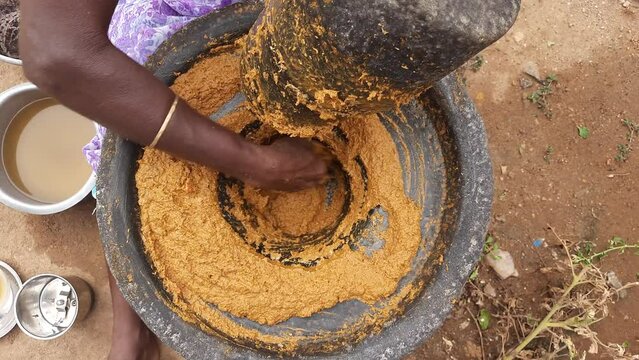 Hand using a large authentic millstone, medieval utensil for grinding masala paste and cereals into flour.
