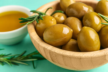 Bowl with ripe olives on turquoise background, closeup