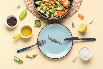Plate and frying pan with tasty vegetables on yellow background