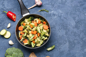 Frying pan with tasty vegetables on blue background
