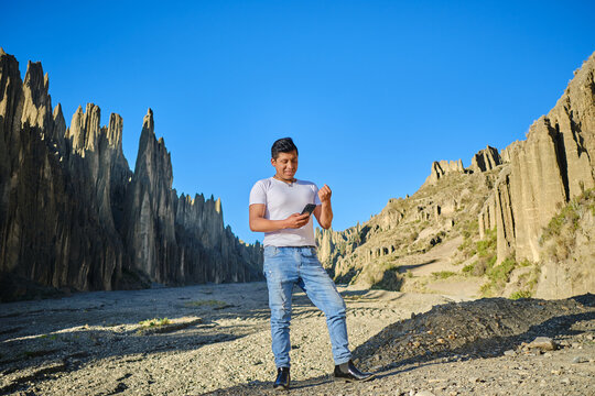 latin man on mountain trip looking at his cell phone