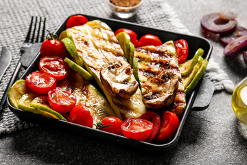 Baking dish with tasty grilled vegetables on grunge background