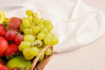 Wicker basket with different fresh fruits on pink background