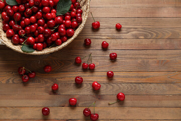 Wicker basket with sweet cherries on wooden background