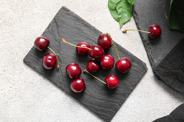 Board with sweet cherries on white background