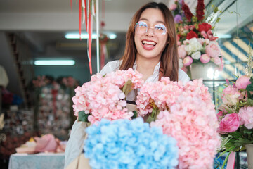 Portrait of young beautiful Asian woman florist with floral bunch delivery, smiling and looking at camera, lovely business entrepreneur, flower shop happy work, brightly colorful flora bouquet store.