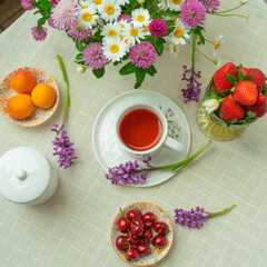 Obraz na płótnie Canvas Morning tea with flowers and fruits on the terrace of a country house. Flat lay