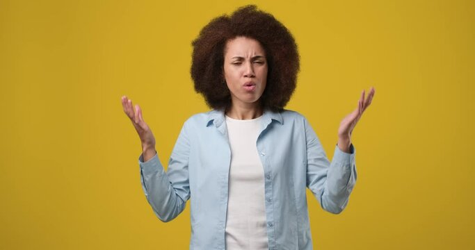 Emotional incomprehensible african american woman shrugging shoulders and raising hands asking Why standing over orange studio background