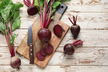 Board of fresh beets with green leaves on wooden background