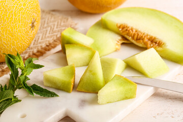 Board with pieces of sweet melon and mint, closeup