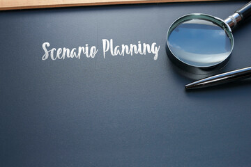 The word Scenario Planning is written on the black chalkboard with a pen, and magnifying glass