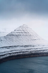 View of snowy Hvíthamar mountain in the Faroe Islands on a misty day