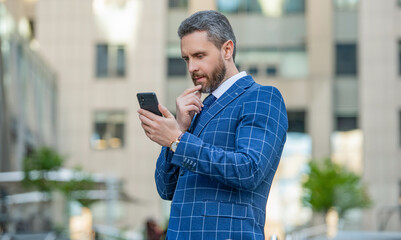 thinking businessman messaging on phone outside. photo of businessman messaging