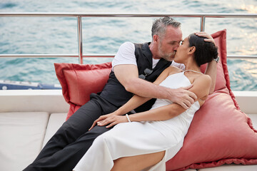 Obraz premium couple lying on big pillow and kissing in luxury yacht