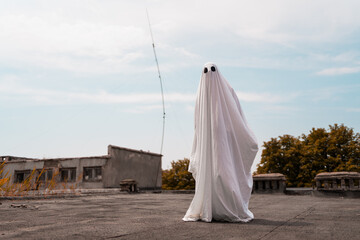 Ghost covered with a white ghost sheet on street. Halloween Concept.