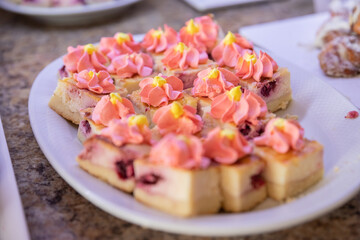 Assorted cakes, pastries ans small sweet desserts with strawberry in a restaurant buffet close up.Catering banquet table with appetizers, colored sweet cakes with chocolate and cream.