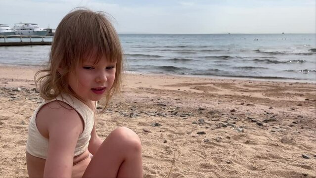 Little cute girl by the sea. Child playing in the sand on the beach