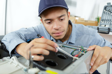 young serviceman working on electrical appliance