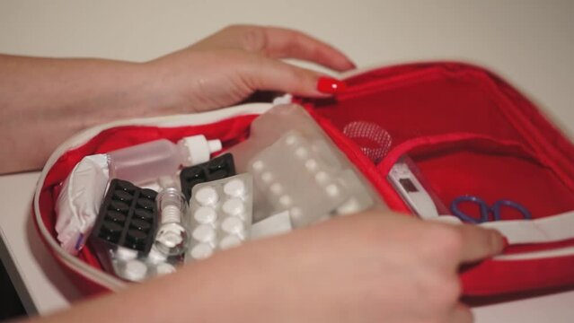 a caucasian woman takes out pills from a blister pack. a woman opens a first aid kit with pills. woman and first aid kit. close-up. slow motion video. High-quality shooting in Full HD