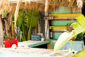 Fototapeta premium Counter of sunny surf hire shop on beach with radio and signs to beach and pool