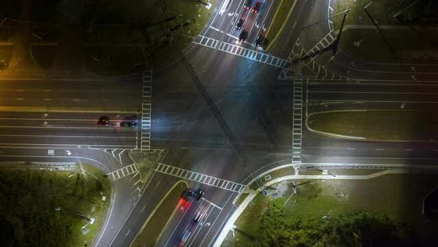 Aerial view of american wide multilane street intersection with traffic lights and moving cars at night. Timelapse of transportation in USA
