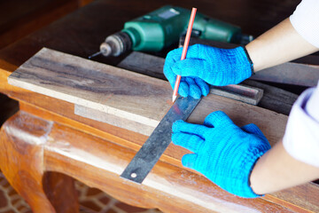 Close up carpenter hands wears   blue gloves is measuring wood board by using pencil and ruler. Concept , Carpenter working, construction, design, DIY. Renovate woodwork at home, Carpentry.