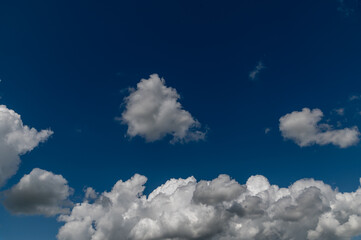 Naklejka na ściany i meble Stormy and fluffy white and grey clouds against a bright blue sky