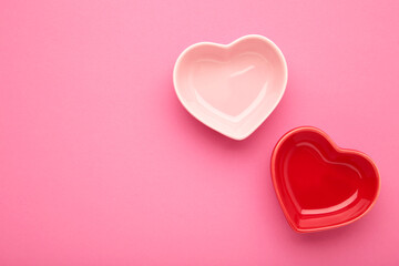 Red and pink heart shaped bowls on pink background.