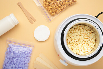 Electric wax warmer or wax heater with wax drops inside on beige background.