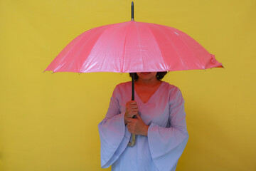 An Asian woman standing under a red umbrella.
