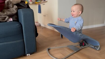 baby plays swinging on a rocking chair. happy family kid dream concept. baby plays a funny video swings on a swing chair for babies to lifestyle sleep