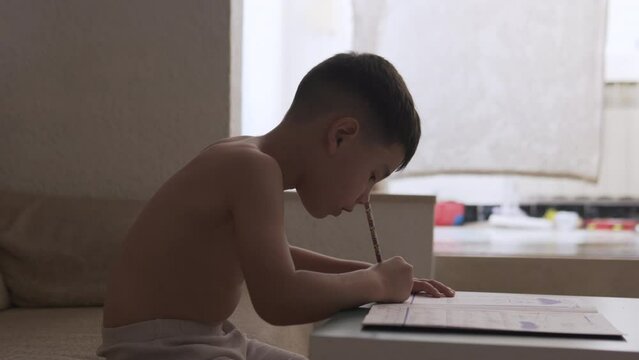 Kid practicing and learning to write during summer vacation at home. Practice homwork on holiday. Handheld backlit domestic childhood scene