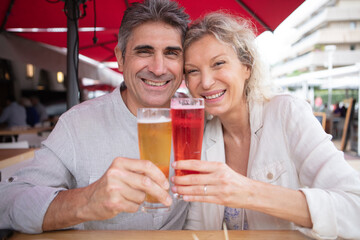 happy mature couple toasting sat in restaurant terrace