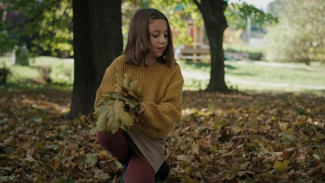 Little girl looking for leaves in public park during the autumn. Shot with RED helium camera in 8K.  