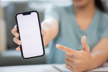 Delivery app. Close-up of smiling young woman in hand showing smartphone with blank screen for mockup woman working with boxes at home