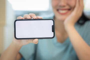 Delivery app. Close-up of smiling young woman in hand showing smartphone with blank screen for mockup woman working with boxes at home