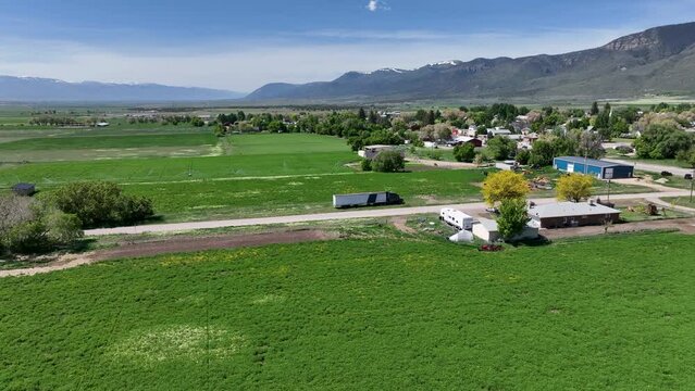 Aerial mountain valley green summer farms Utah. Rural farming community agricultural economy. Spring summer season weather mountain valley agriculture field harvest. Seasonal. weather environment.