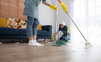 Cleaning service. Dark-haired woman wearing a white hat and yellow gloves cleaning the floor