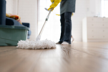 Close up of young woman cleaning floor with mop. Housework concept