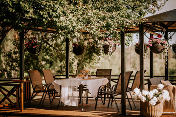 A white table is laid on the terrace and decorated with flowers in summer, which are hung in pots at sunset