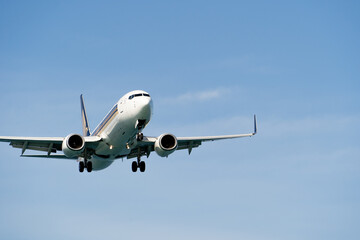 Close-up view of a landing plane against a blue clear sky. Commercial flights on an airliner. Air Transport. Place for text, copyspace.