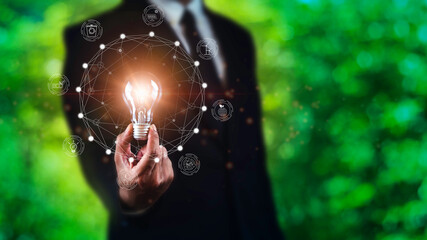 Businessman holding Bright light bulb with ecology concept against natural background.