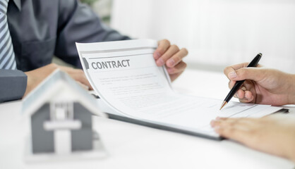 A real estate agent with a home model is talking to clients about renting a house and buying home...