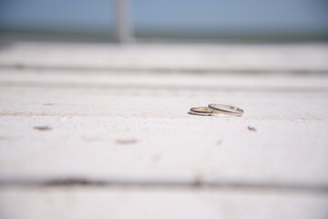 White gold wedding rings on a wooden table by the sea.